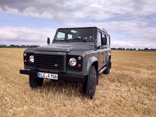 Der Defender von vorn auf einem abgeernteten Getreidefeld unter blauem Himmel