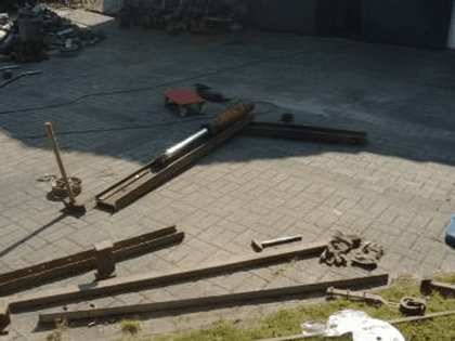Alte Eisenträger und ein Hydraulikzylinder liegen ausgebreitet auf dem Pflaster