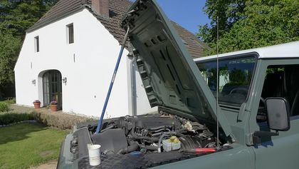 Der Defender mit weit geöffneter Motorhaube vor dem Haus