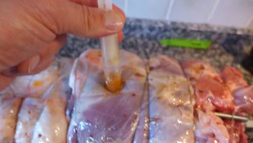 Mit einer Spritze wird Marinade in das Fleisch gespritzt