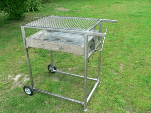 Der fahrbare Edelstahlgrill auf dem Rasen, schräg von vorn