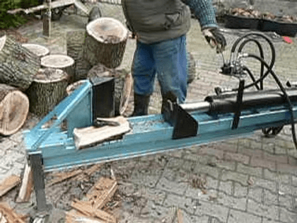Der blau lackierte Holzspalter beim Spalten eines Holzklotzes