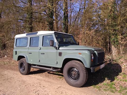 Der Defender schräg von vorn auf einem Waldweg