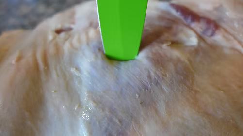 Ein Messer mit grüner Klinge sticht einen Schlitz in das Fleisch