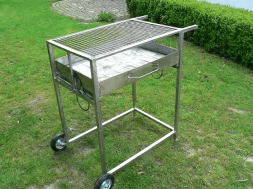 Der fertige Edelstahlgrill mit Rost auf dem Rasen vor einer Hecke
