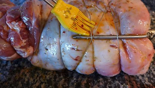 Die mit Draht umwickelten Keulen werden mit Marinade bepinselt
