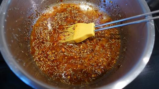 Die rote Marinade mit Kräutern in einer Schüssel, darin ein Pinsel
