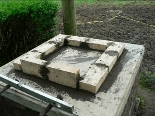 Ein Rahmen aus Schamottesteinen auf der Betonplatte des Sockels