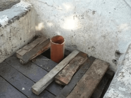 Der Brunnenkopf mit Rohr, Bohlen und abgeplatzter Wand