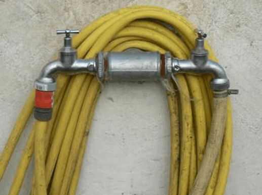 Ein gelber Wasserschlauch mit einem Verteiler und zwei Wasserhähnen