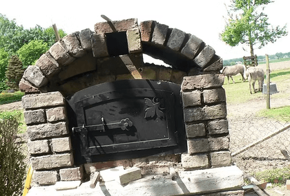 Die fertige Front mit Rundbogen aus Feldbrandsteinen und der schwarzen Ofentür