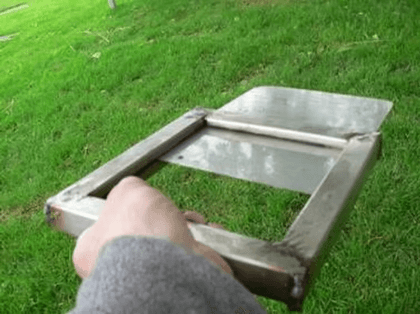 Eine Hand hält einen selbst gebauten Schieber aus Edelstahl