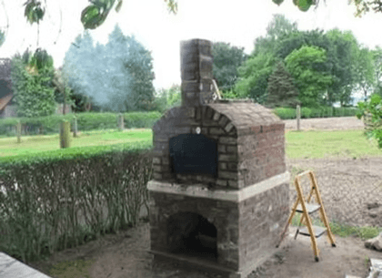 Der fertige Ofen mit hohem Schornstein, aus dem Rauch aufsteigt